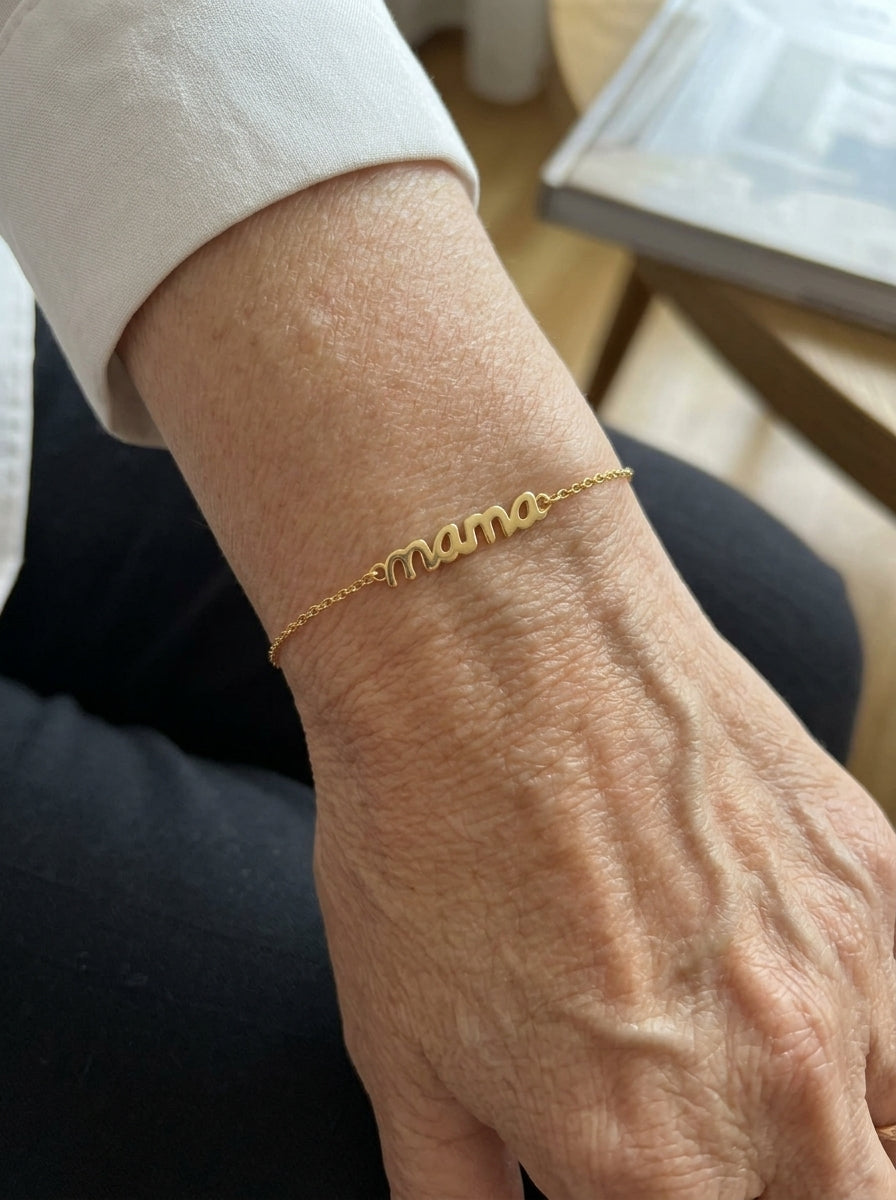 Pulsera dorada con la palabra mama en la muñeca