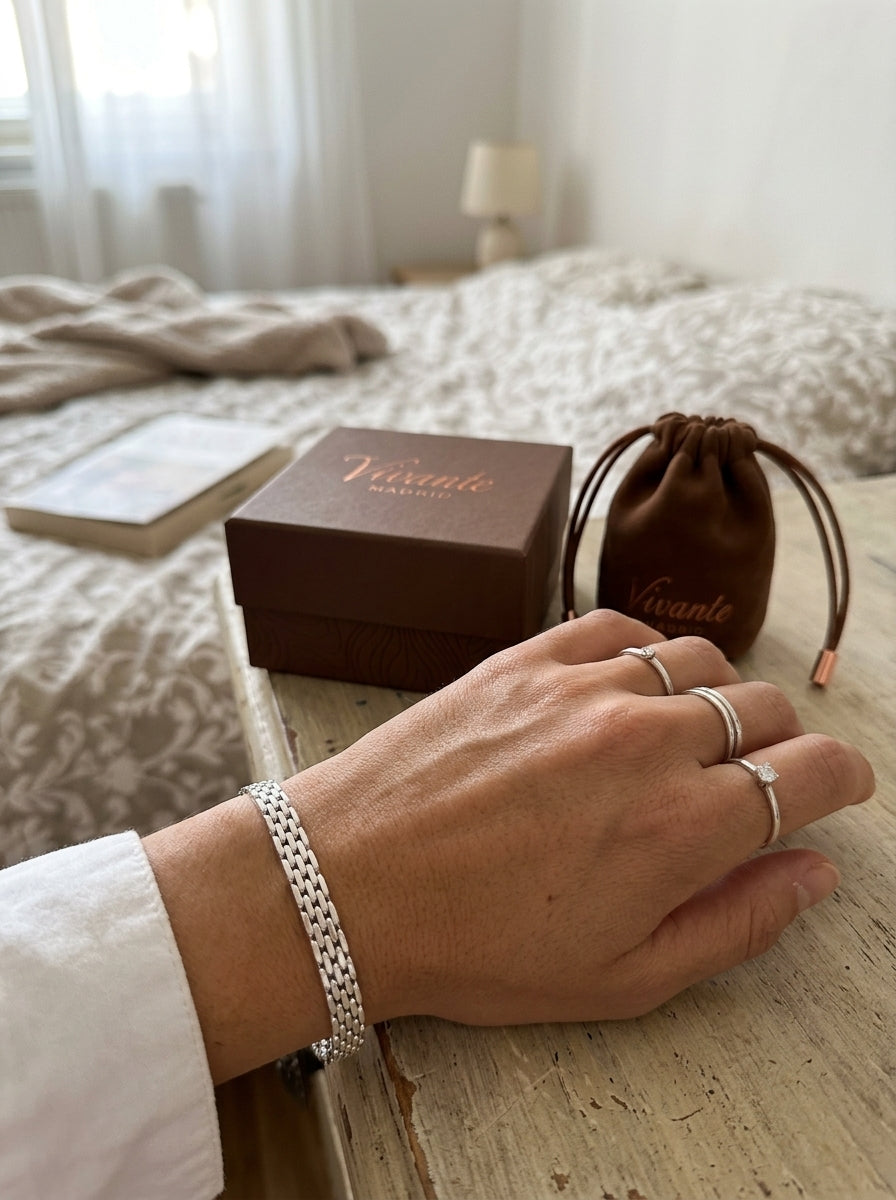 Mano con anillos y pulsera de plata junto a la caja y la bolsa de regalo de Vivante Madrid